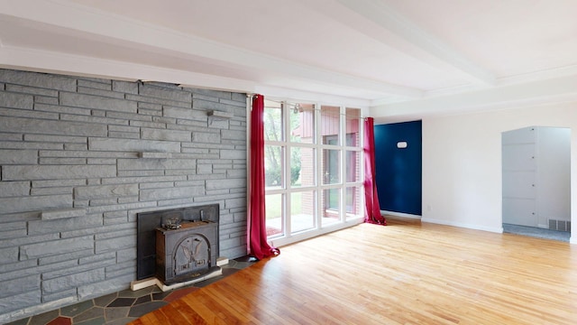 unfurnished living room with a wealth of natural light, visible vents, beamed ceiling, and wood finished floors