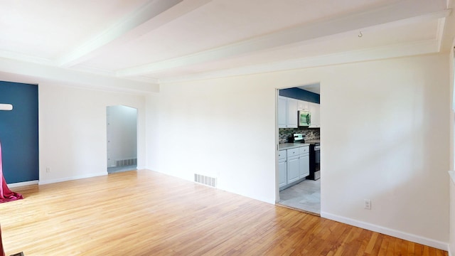 unfurnished room featuring light wood-type flooring, visible vents, beamed ceiling, and baseboards