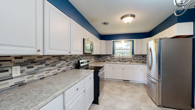 kitchen featuring stainless steel appliances, visible vents, backsplash, white cabinetry, and a sink