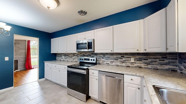 kitchen featuring appliances with stainless steel finishes, white cabinets, visible vents, and backsplash