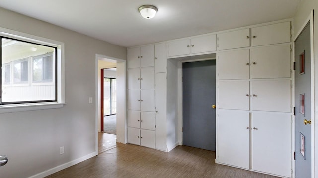 unfurnished bedroom with a closet, baseboards, and wood finished floors