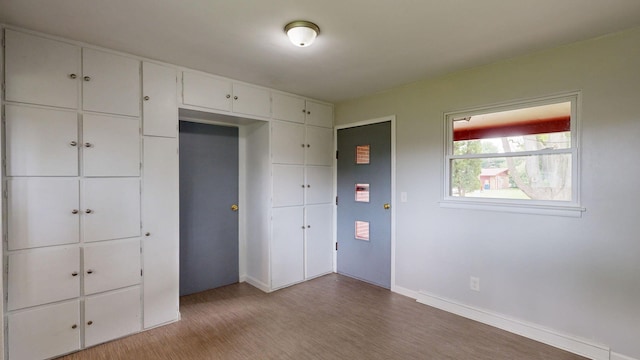 unfurnished bedroom with a closet, wood finished floors, and baseboards