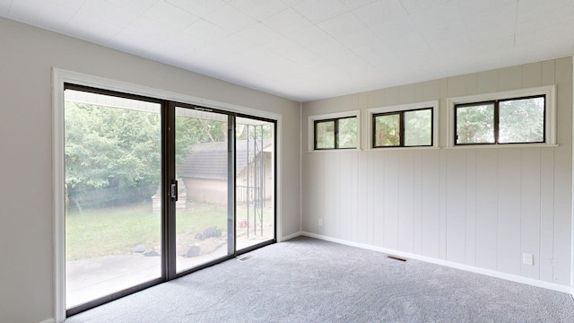 carpeted empty room with a healthy amount of sunlight, visible vents, and baseboards