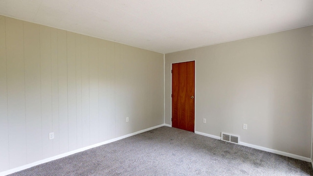 empty room featuring carpet, visible vents, and baseboards