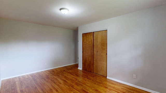 unfurnished bedroom featuring a closet, baseboards, and wood finished floors