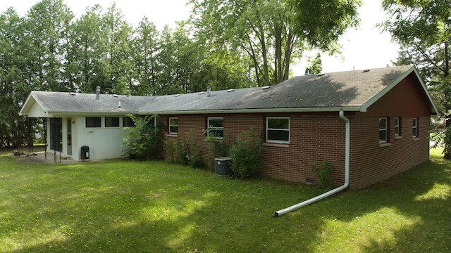 rear view of house with a yard, a patio area, central AC, and brick siding