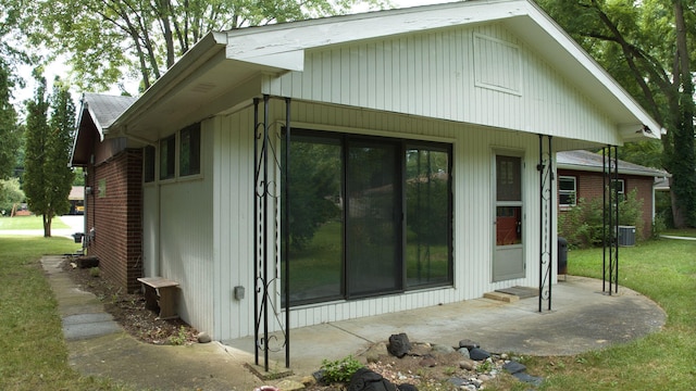 view of home's exterior with central air condition unit, a yard, and brick siding