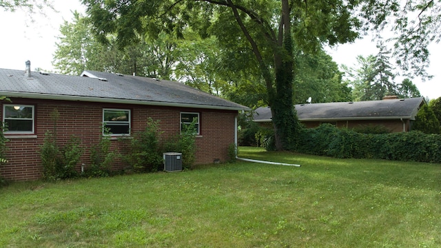 exterior space with central AC, brick siding, and a lawn