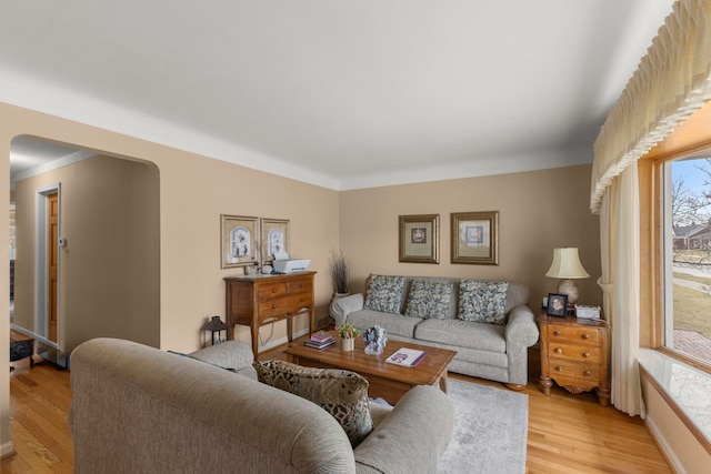 living room featuring light wood finished floors, baseboards, and arched walkways