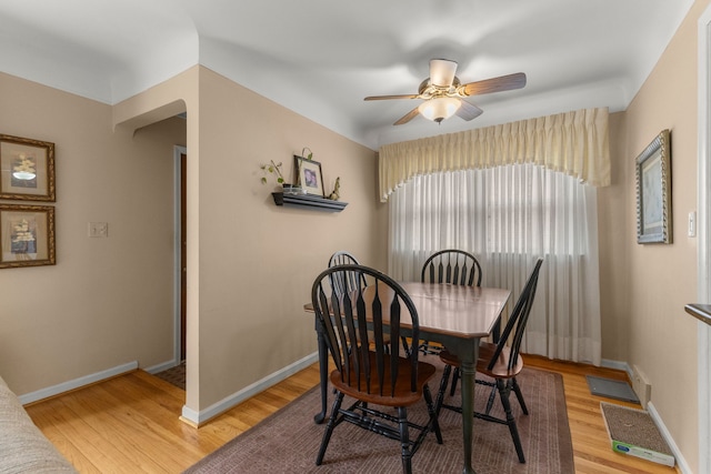 dining space featuring light wood-type flooring, baseboards, and a ceiling fan