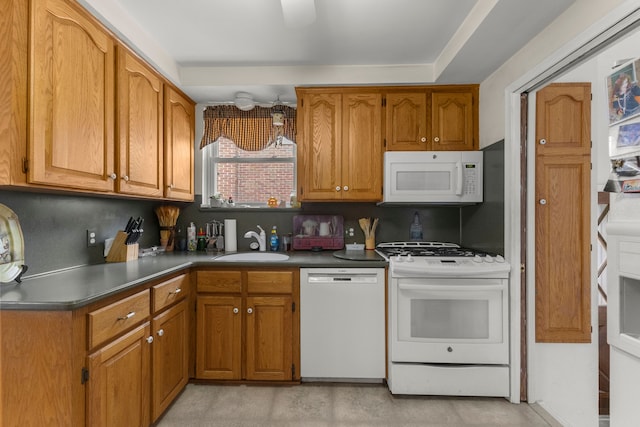 kitchen with brown cabinetry, white appliances, and a sink