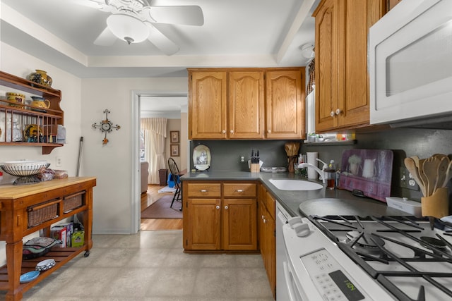 kitchen with white appliances, a ceiling fan, brown cabinetry, and a sink