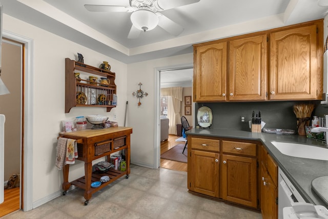 kitchen featuring dishwasher, dark countertops, ceiling fan, brown cabinets, and a sink