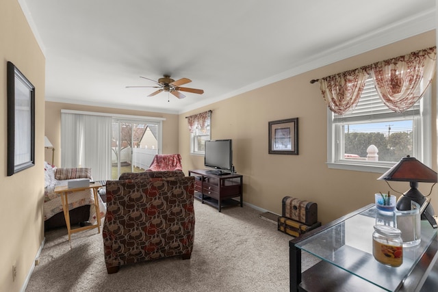 carpeted living area featuring baseboards, a ceiling fan, and crown molding