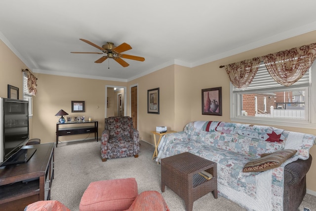 living area with crown molding, baseboards, ceiling fan, and carpet flooring