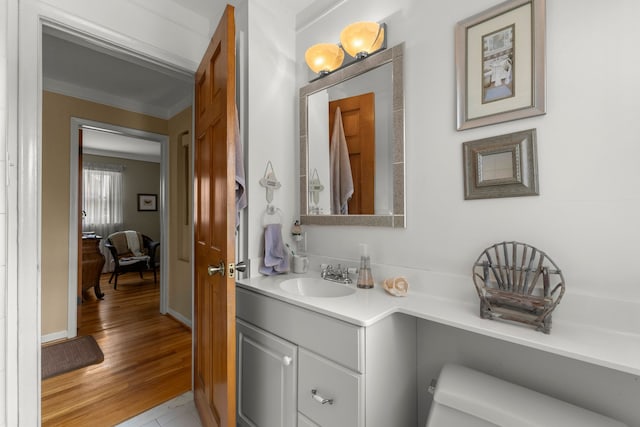 bathroom featuring ornamental molding, wood finished floors, and vanity