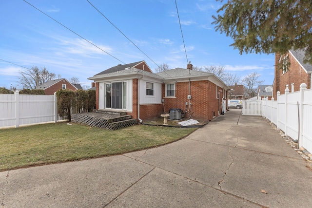 back of property with driveway, central AC unit, fence, a yard, and brick siding