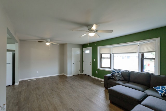 unfurnished living room featuring ceiling fan, baseboards, and dark wood finished floors