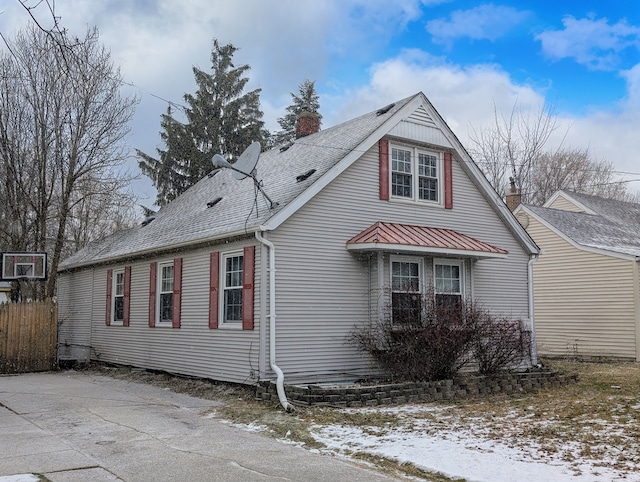 view of home's exterior with metal roof, roof with shingles, fence, and a chimney