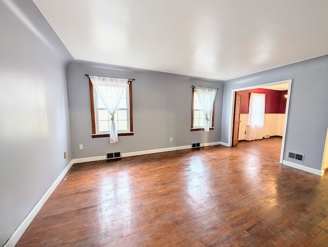 spare room with visible vents, dark wood-type flooring, and a wealth of natural light