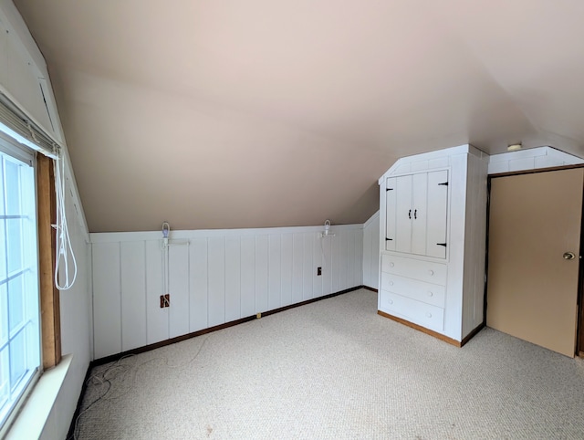 bonus room featuring vaulted ceiling and light colored carpet