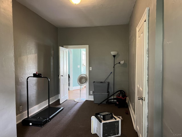 exercise area with dark colored carpet and baseboards