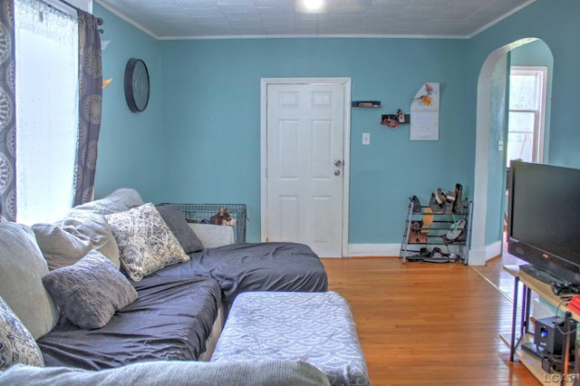 living room with arched walkways, crown molding, baseboards, and wood finished floors