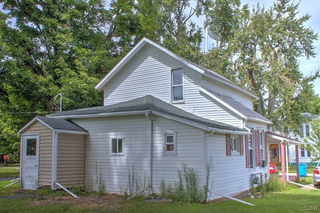 view of property exterior with roof with shingles and a yard