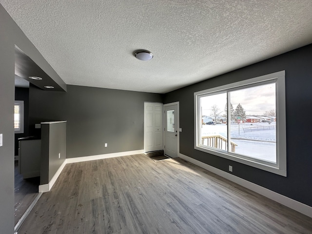 interior space with a textured ceiling, baseboards, and wood finished floors