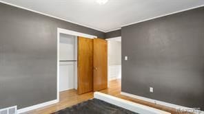 bedroom with baseboards, visible vents, and wood finished floors