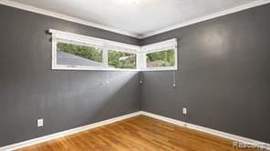 empty room featuring crown molding, wood finished floors, and baseboards