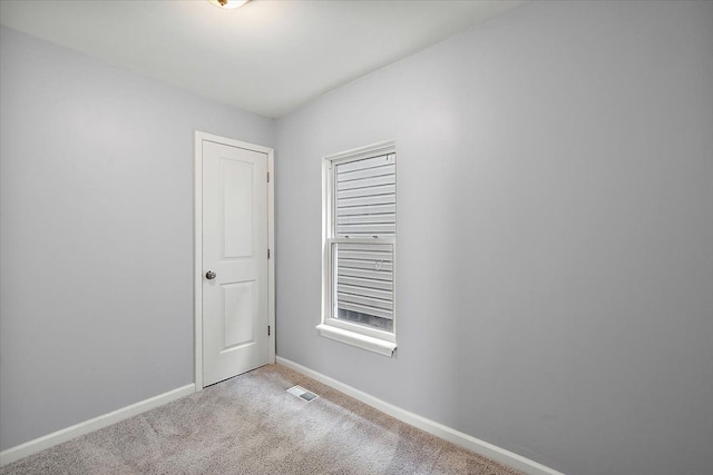 empty room featuring carpet floors, visible vents, and baseboards