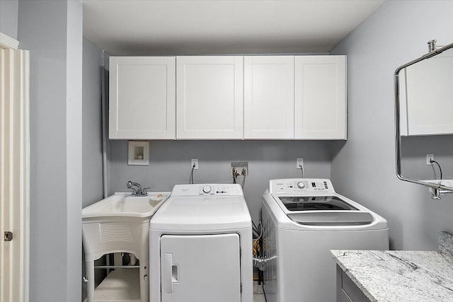 clothes washing area with washer and clothes dryer, a sink, and cabinet space