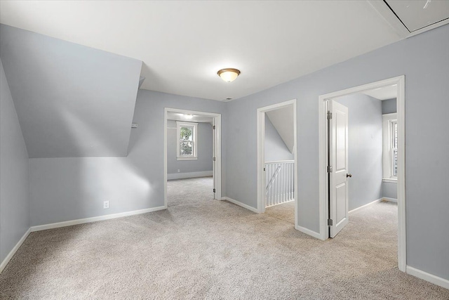 additional living space featuring lofted ceiling, carpet, attic access, and baseboards