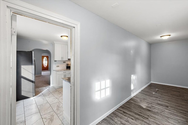 interior space with arched walkways, marble finish floor, and baseboards