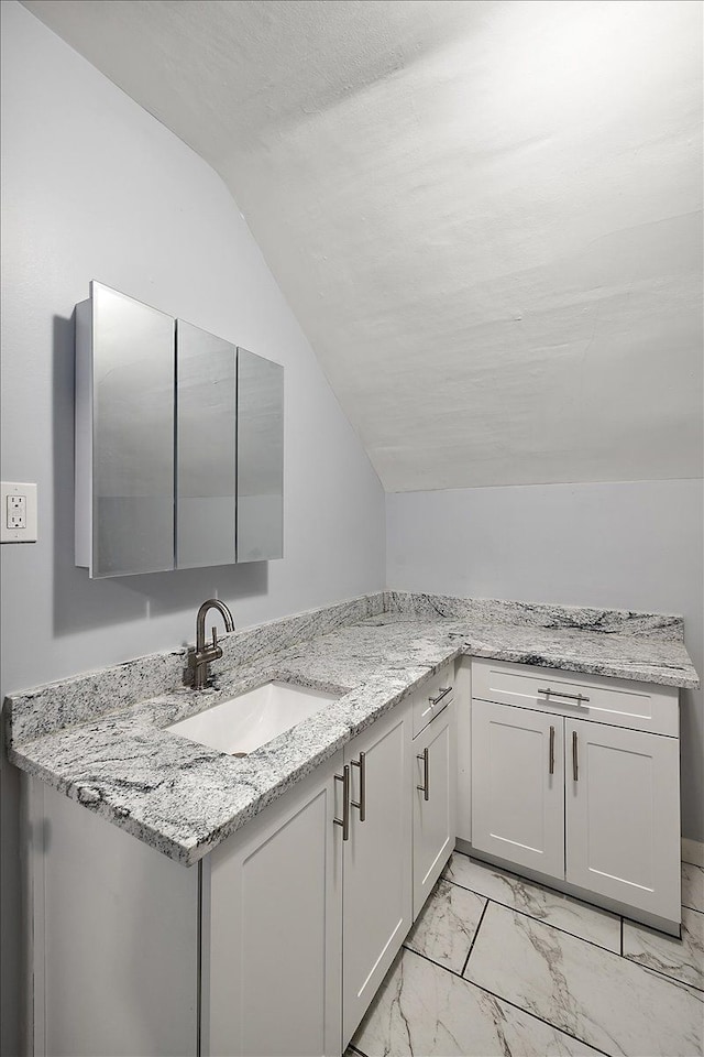 bathroom featuring lofted ceiling, marble finish floor, and vanity