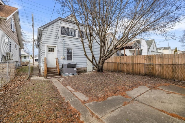 back of property with entry steps, a fenced backyard, and cooling unit