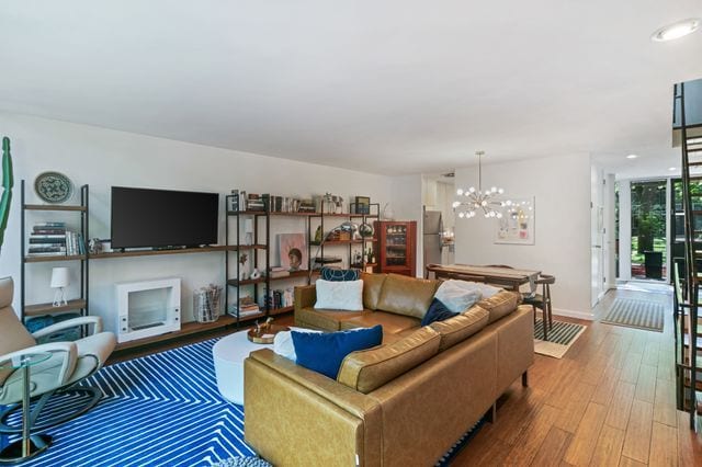 living area featuring baseboards, an inviting chandelier, and wood finished floors