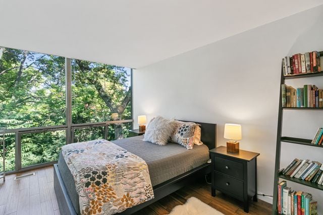 bedroom featuring a wall of windows and wood finished floors