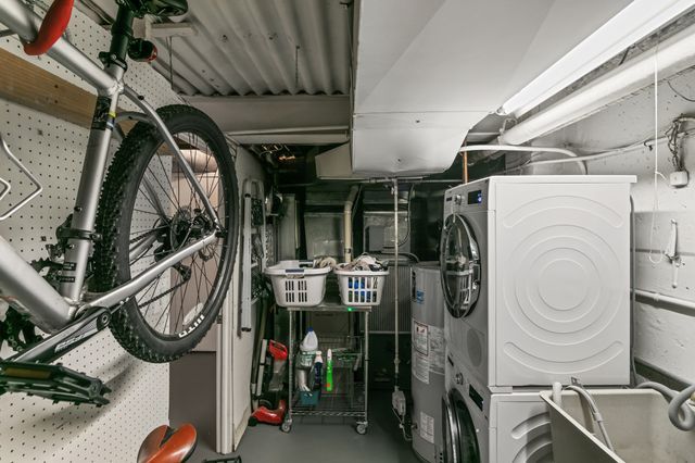 utility room with stacked washer and dryer and gas water heater