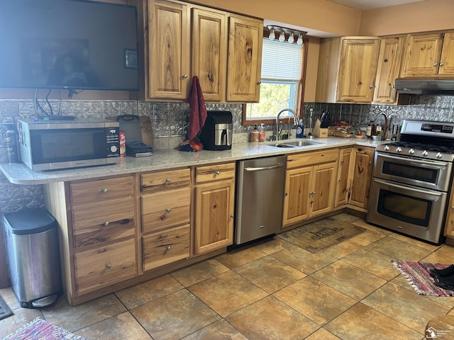 kitchen with a sink, stainless steel appliances, light countertops, under cabinet range hood, and backsplash