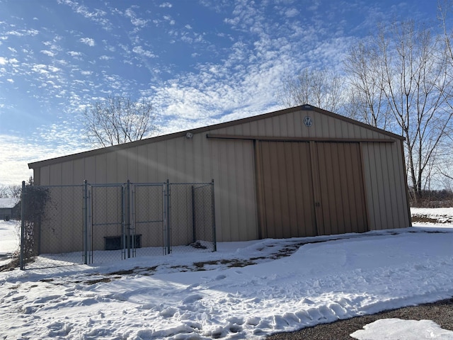 snow covered structure featuring a pole building and an outdoor structure