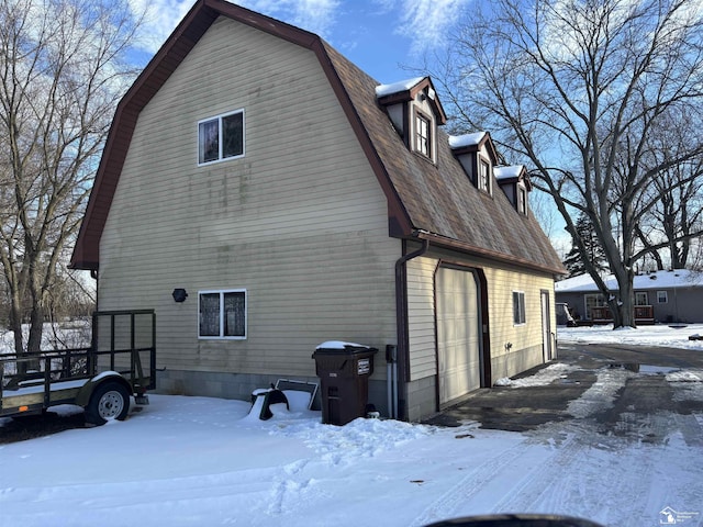 view of snow covered exterior featuring roof with shingles and a gambrel roof