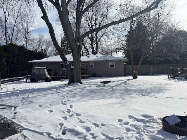 snow covered rear of property featuring fence and a deck