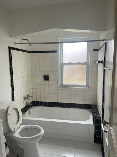 bathroom featuring toilet, tile patterned flooring, and bathing tub / shower combination