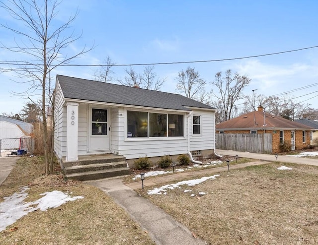 bungalow featuring entry steps, a shingled roof, and fence