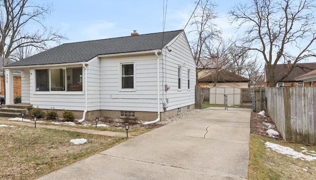 view of side of property with an outbuilding, fence, driveway, roof with shingles, and a chimney