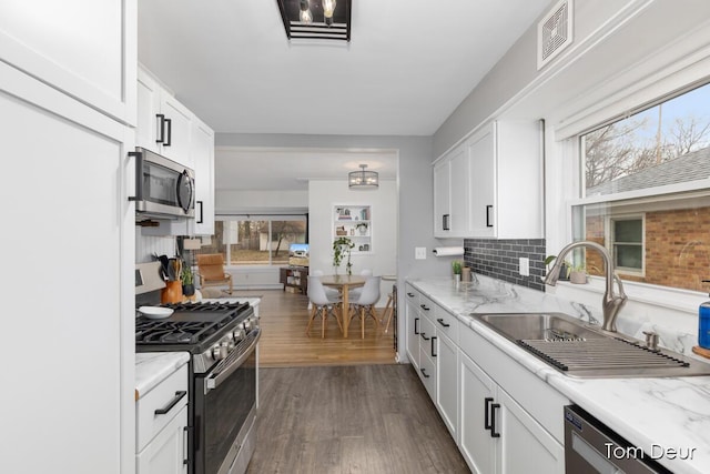 kitchen featuring visible vents, white cabinets, dark wood-type flooring, stainless steel appliances, and a sink