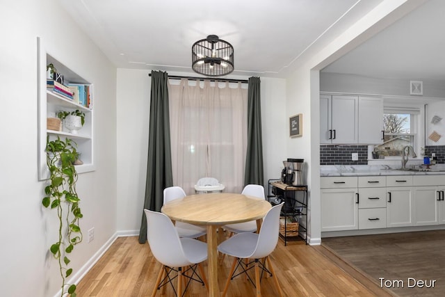 dining area with light wood-style flooring, baseboards, and an inviting chandelier