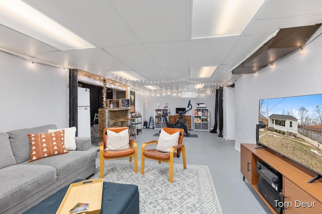 living room featuring concrete flooring and a drop ceiling